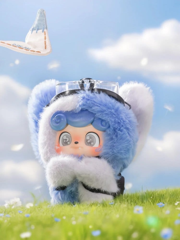 Plush Q kid dream paper airplanes toy with blue hair and white fur on a grassy field with a blue sky background