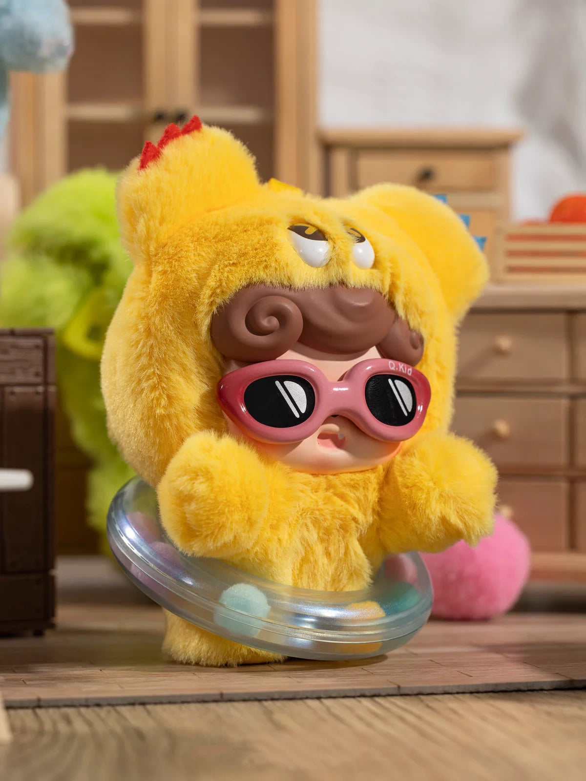 Yellow Delight Q Kid plush toy with sunglasses on a wooden surface