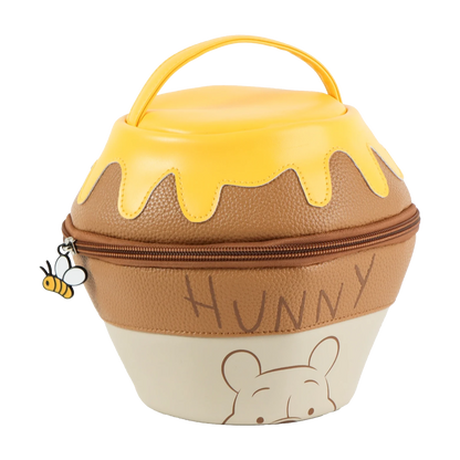 A Winnie the Pooh-style honey pot bag with a yellow honey-drip lid, brown textured body, cream lower section, zipper closure, top handle, and a small bee charm on a white background.