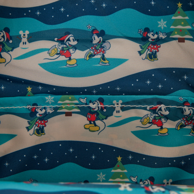 Festive fabric interior lining Mickey Mouse Holiday backpack with Minnie Mouse & Mickey Mouse ice skating on a snowy landscape.