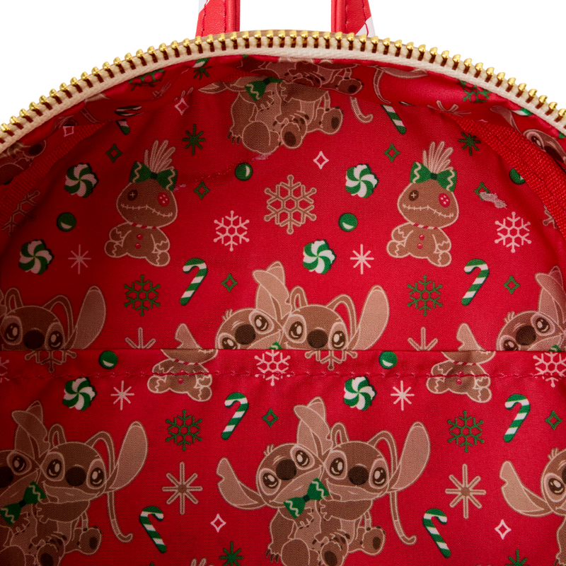 Close-up of fabric lining of Gingerbread stitch Loungefly backpack with a red fabric with Christmas-themed designs including gingerbread Stitch, Angel & Scrumpy, snowflakes, and candy canes