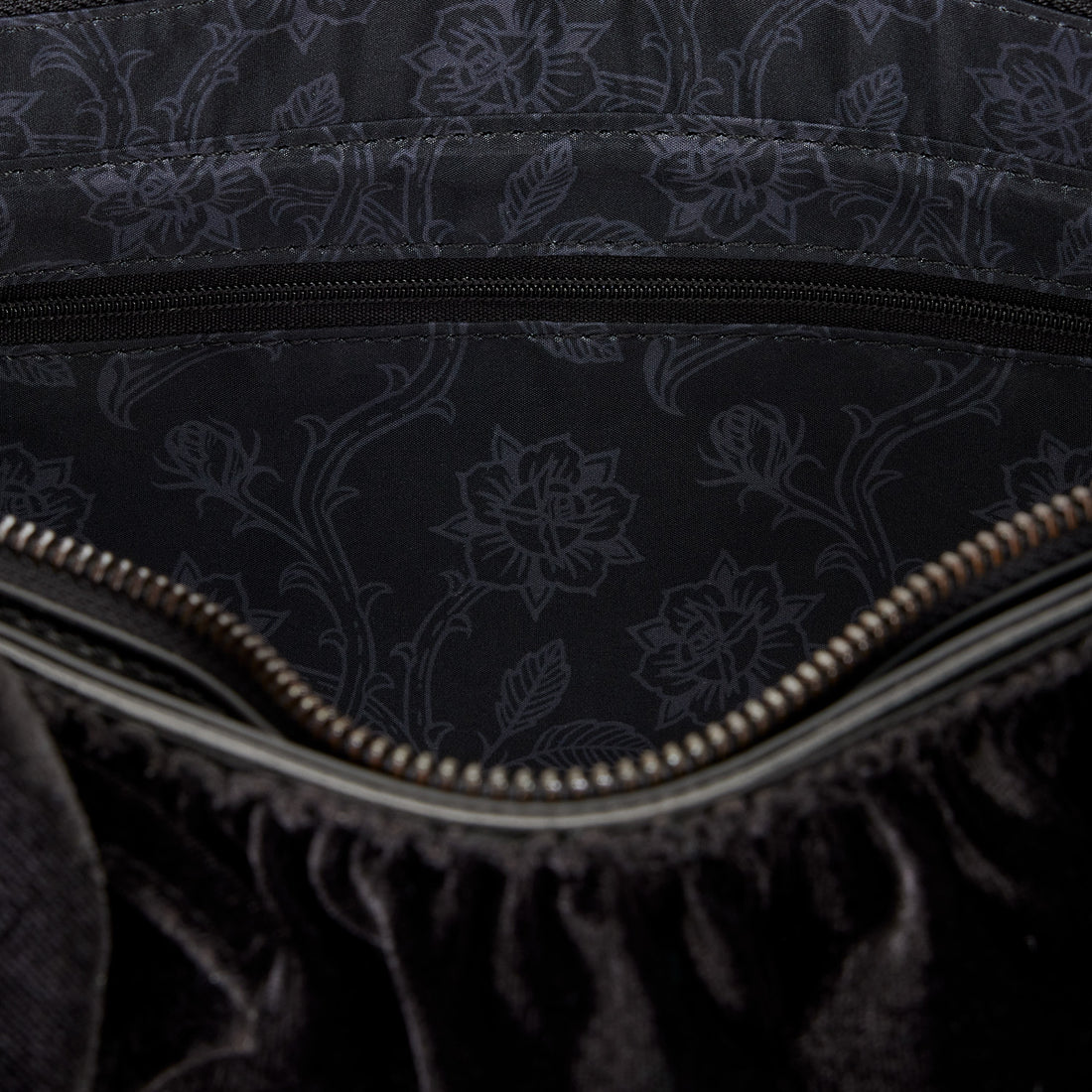 Close-up of a black textured fabric with floral patterns and a zipper.