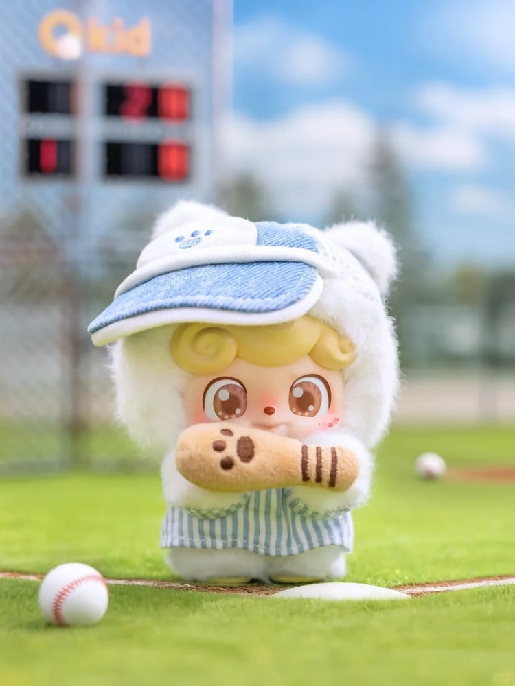 Plush Q kid toy playing baseball on a baseball field with a clear sky.