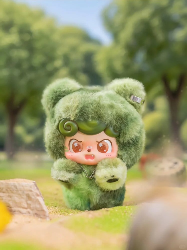 Green Q kid fire in a hole plush toy with a cartoon face in a park setting